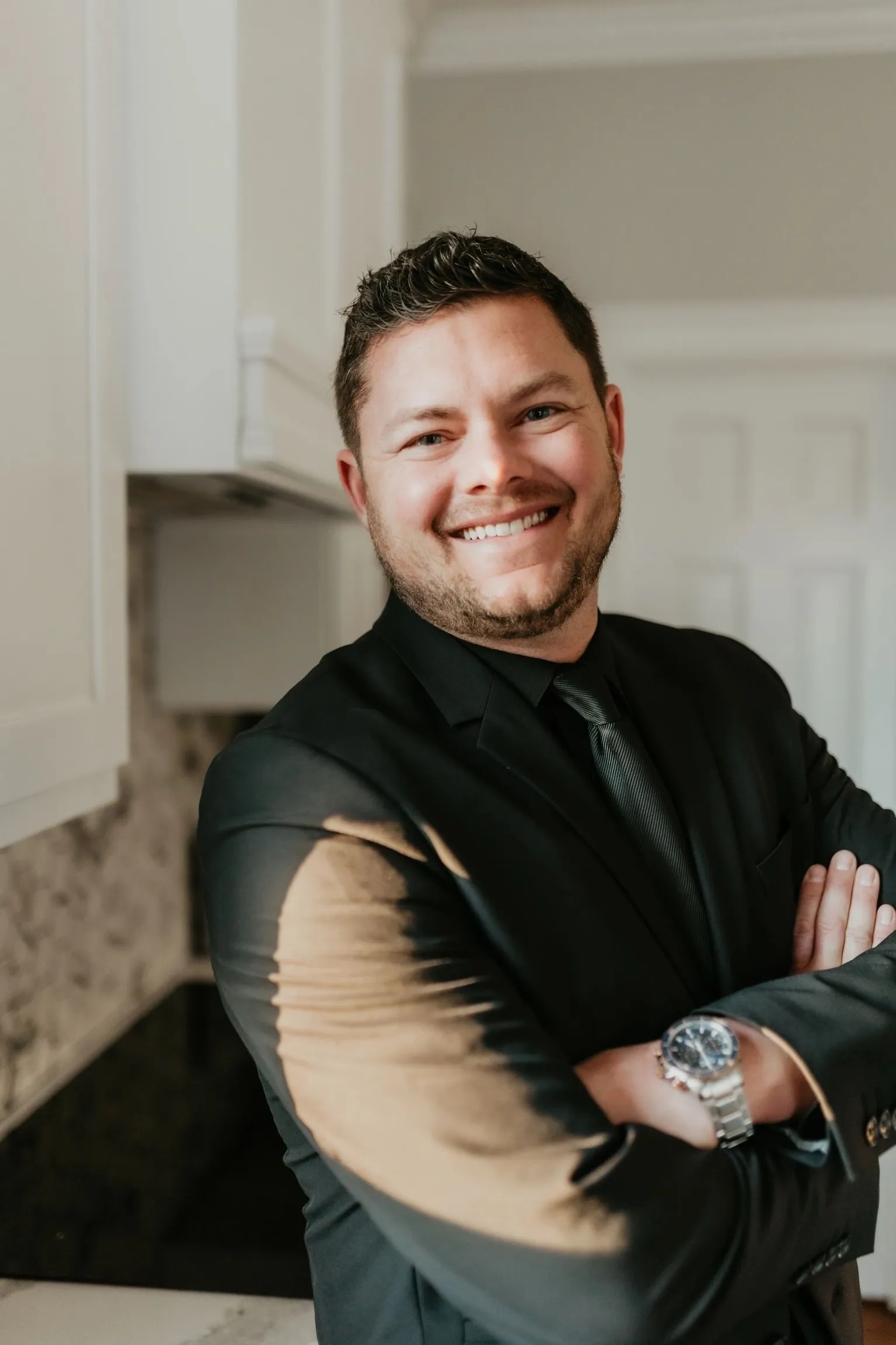 Smiling man in black suit, arms crossed