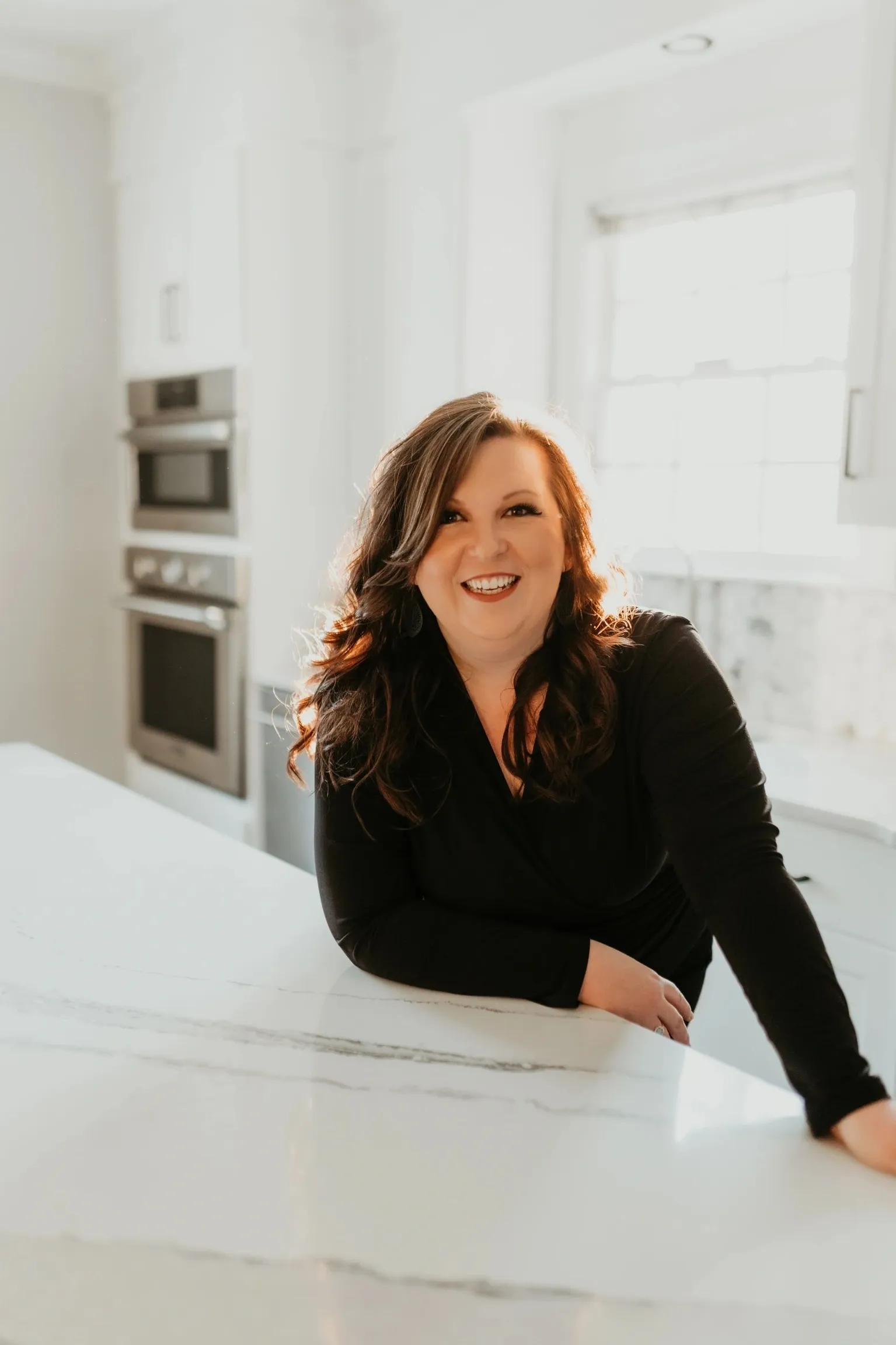 Smiling woman leaning on white marble kitchen counter