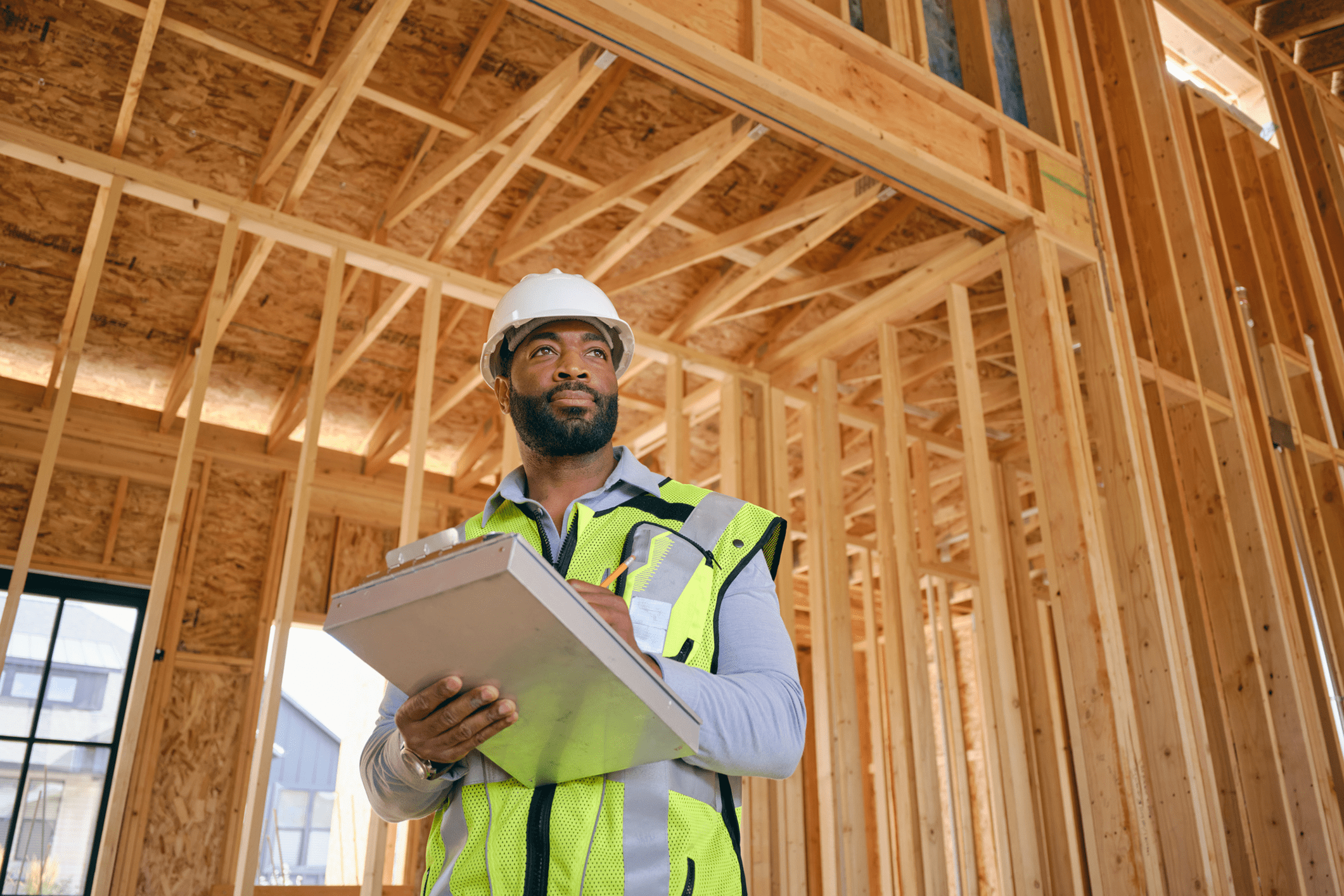 Construction worker with clipboard in wooden framing