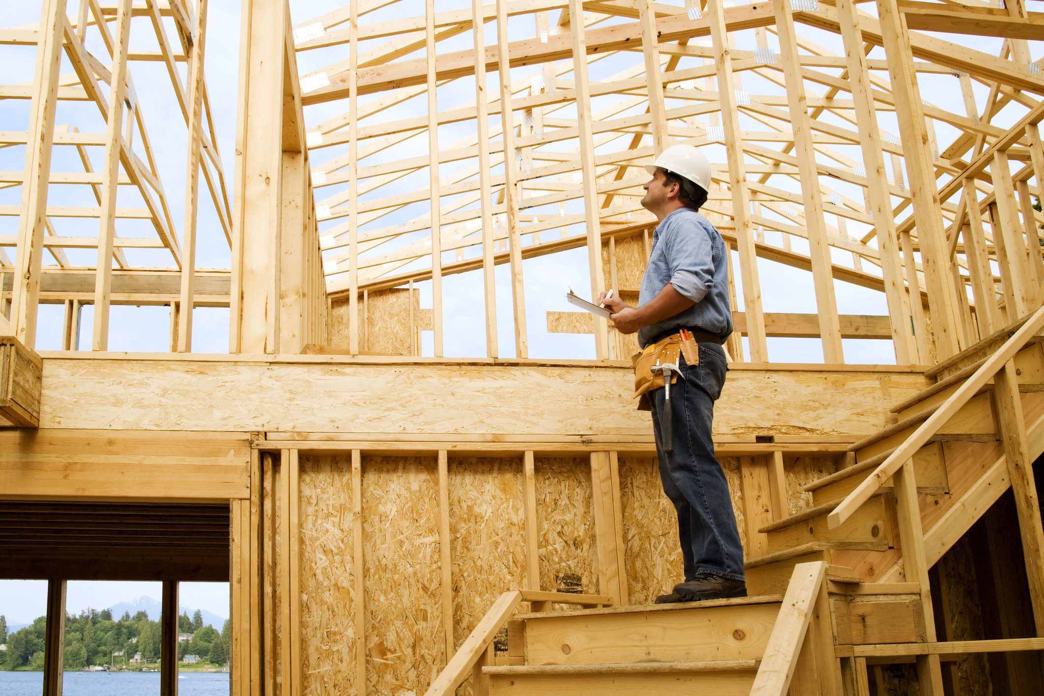 Construction worker inspecting wooden house framing