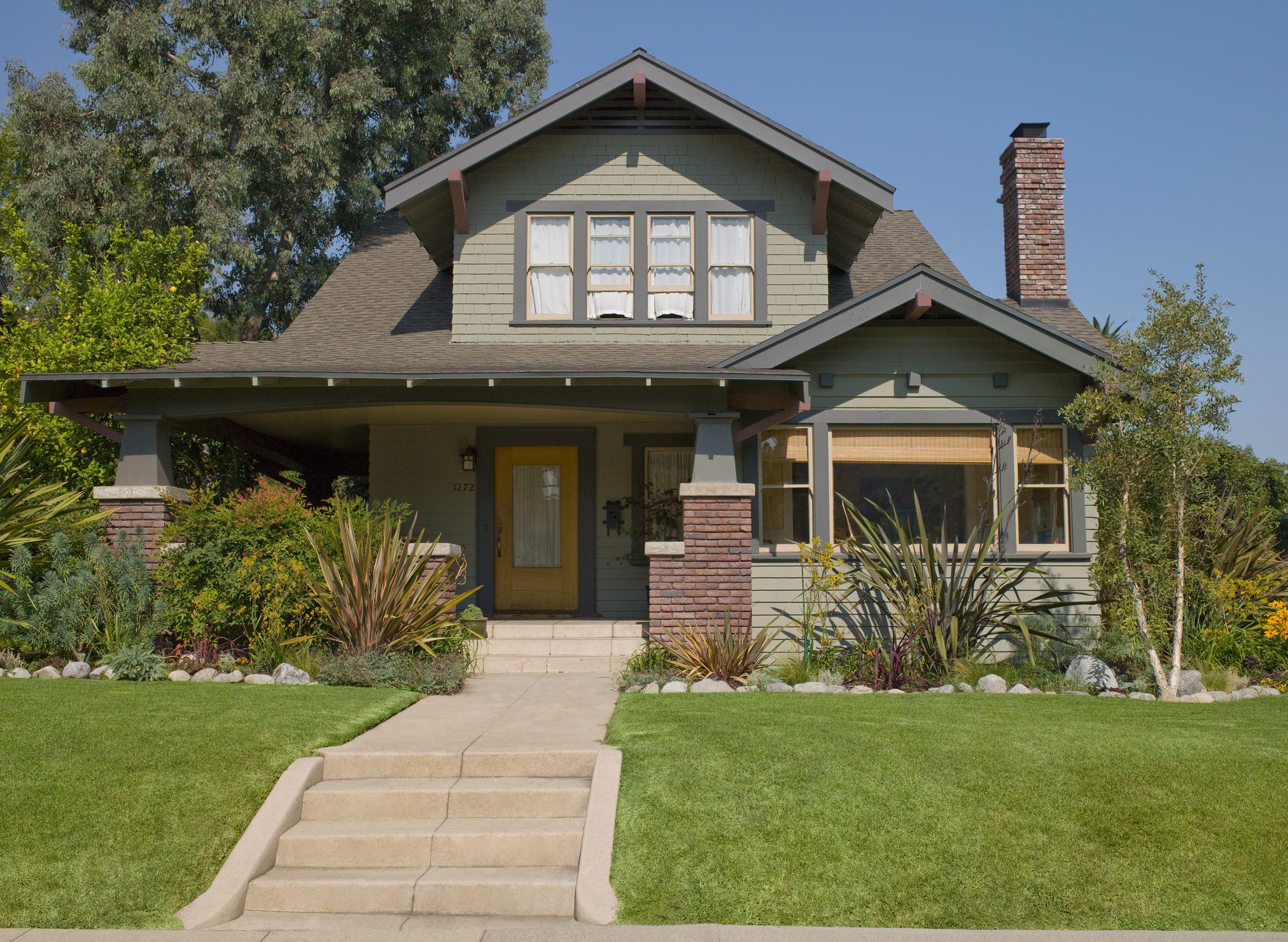 Green Craftsman bungalow with front porch and lawn